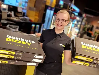 Bilde av butikksjef Bankers pizza holder opp pizzaesker