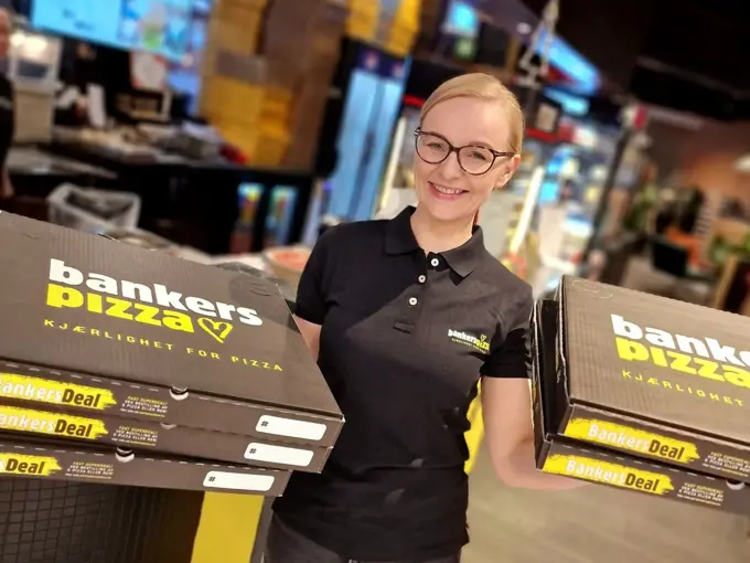 Bilde av butikksjef Bankers pizza holder opp pizzaesker
