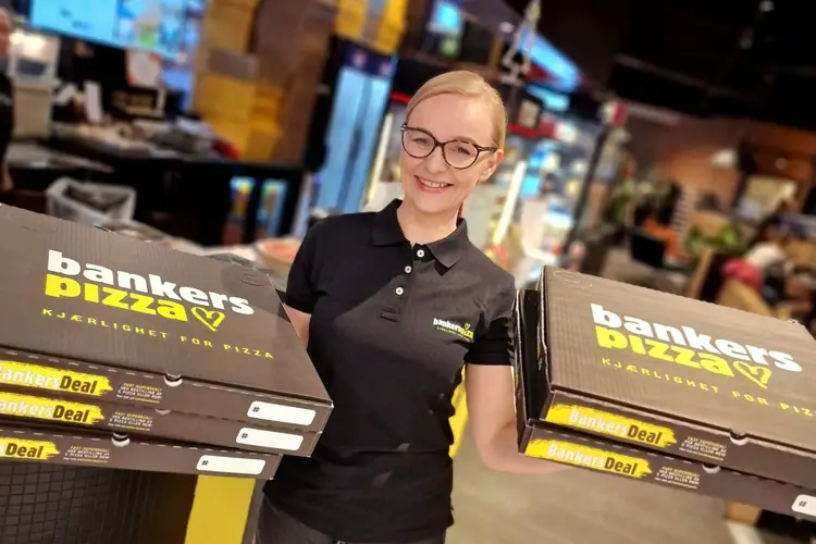 Bilde av butikksjef Bankers pizza holder opp pizzaesker
