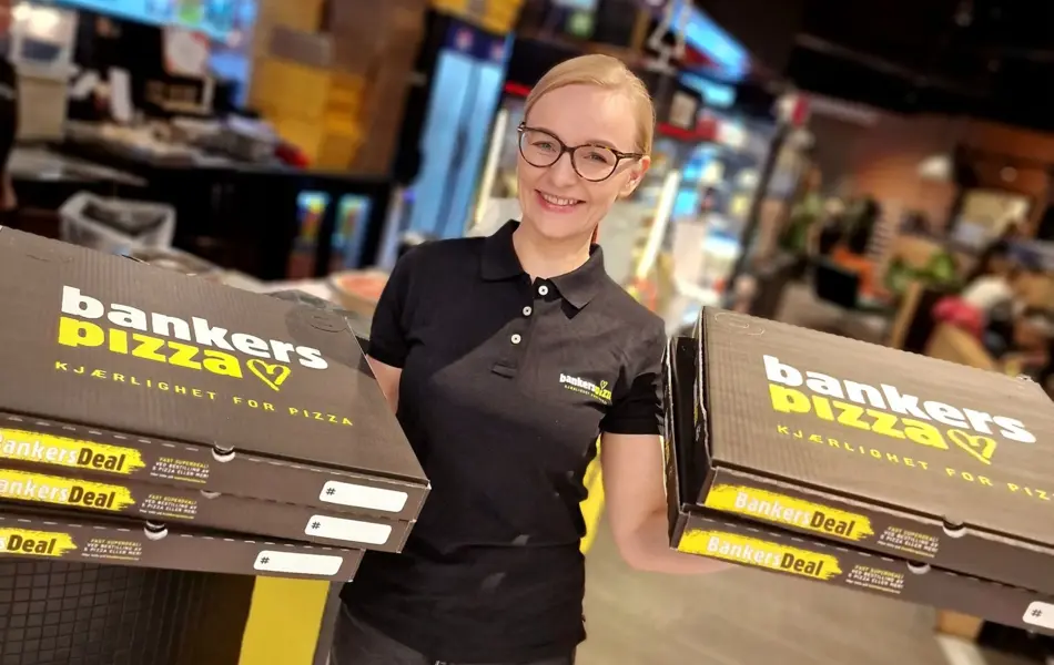 Bilde av butikksjef Bankers pizza holder opp pizzaesker