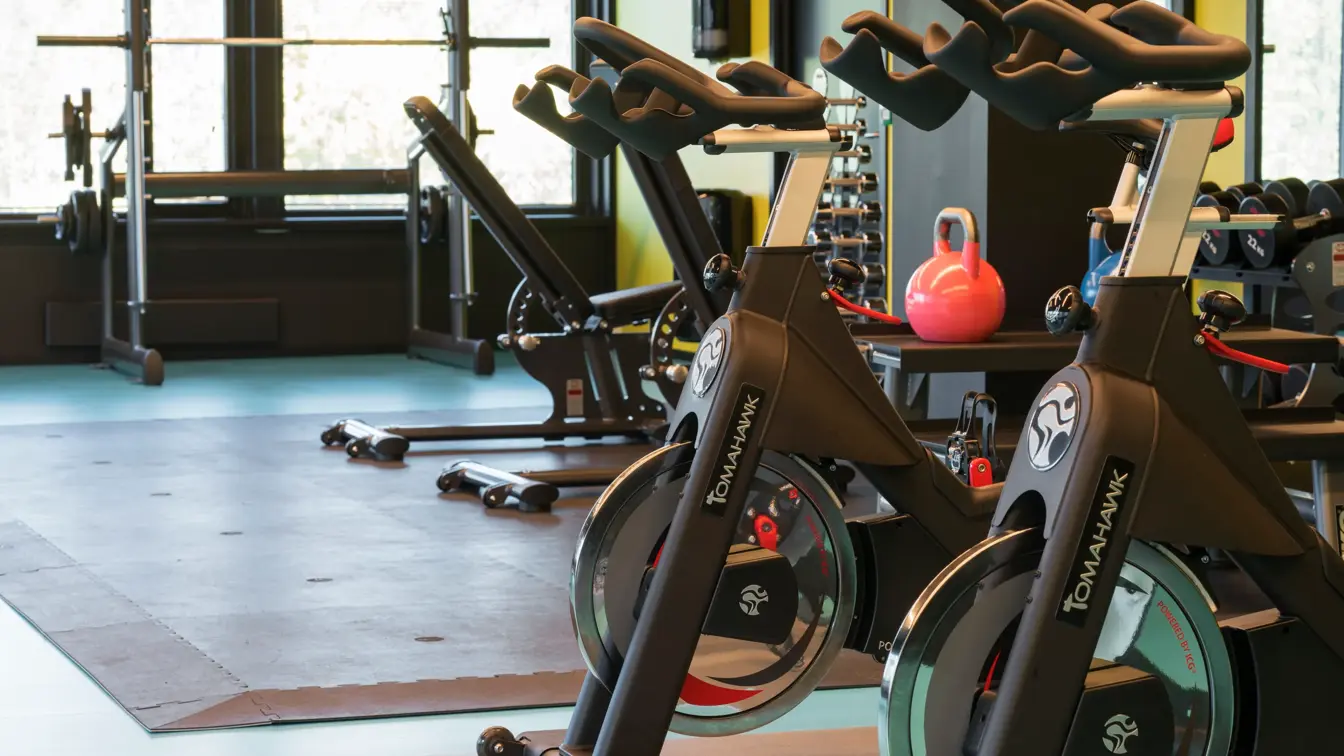 Treningsrom med spinningssykler med gul og grønne farger på vegg og gulv på Thon Hotel Oslo Airport