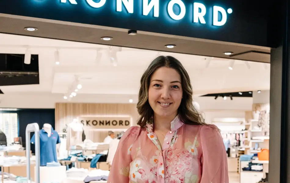 dame i kjole står foran butikk