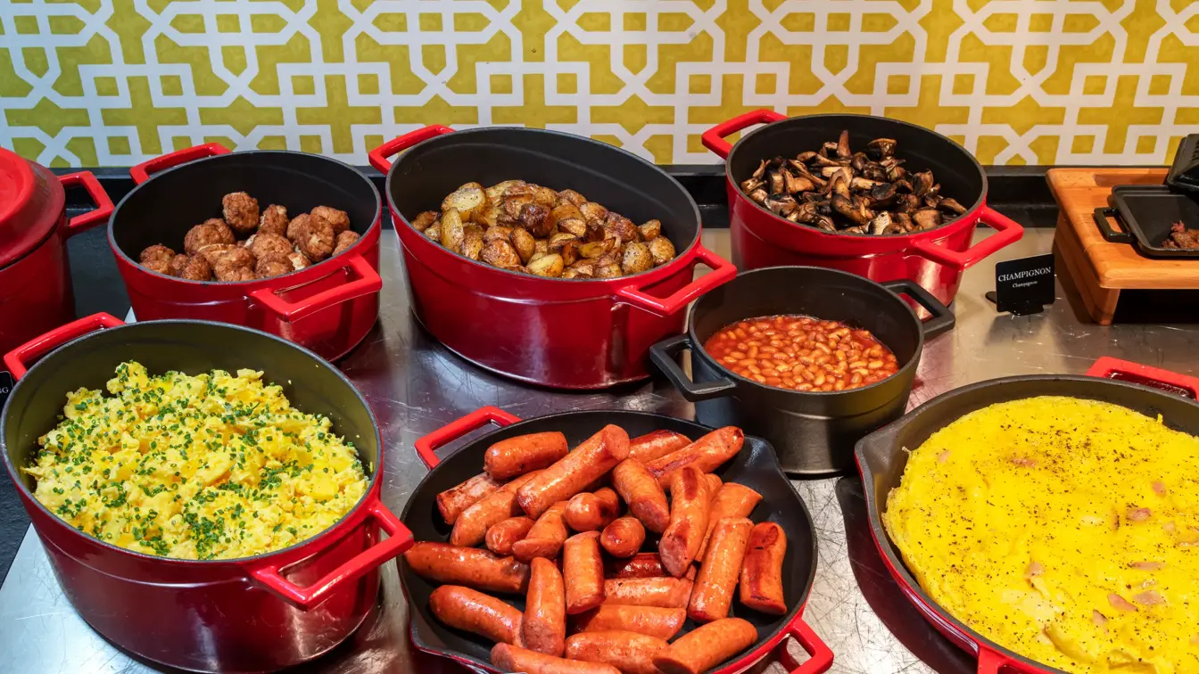 Frokostbuffet, varmmat, pølser, omelett, poteter, sopp, bønner. 