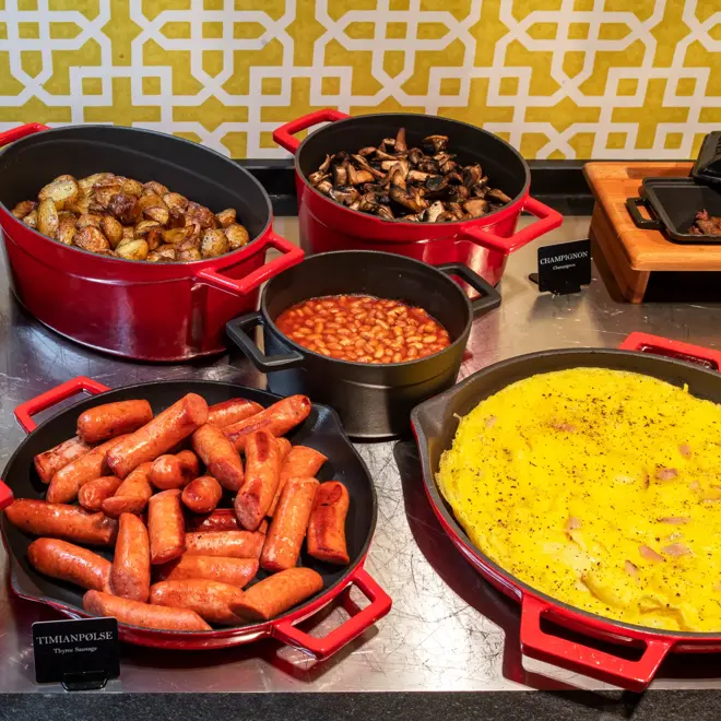 Frokostbuffet, varmmat, pølser, omelett, poteter, sopp, bønner. 