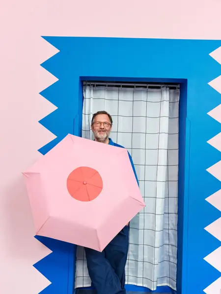 mann, designeren, står med rosa sløyfe paraply fra Lindex