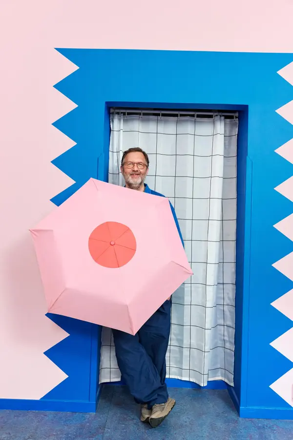 mann, designeren, står med rosa sløyfe paraply fra Lindex