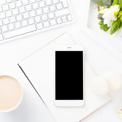 Telefon, tastatur og kaffekopp på et skrivebord