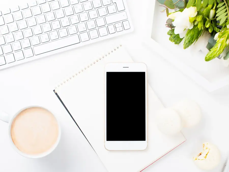 Telefon, tastatur og kaffekopp på et skrivebord