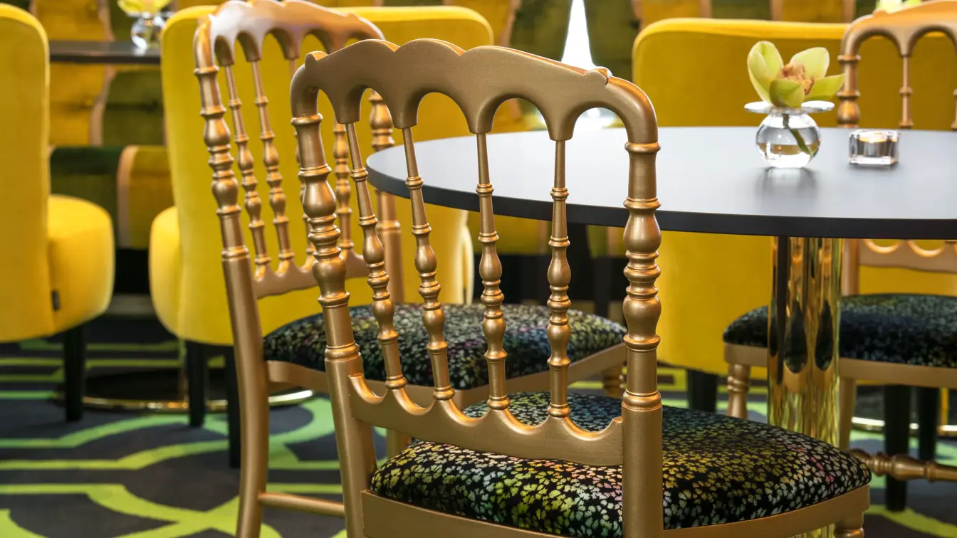 Lounge med mønstret gulvteppe i svart og grønt, gullfargede stoler, lenestoler i gule farger på Thon Hotel Stavanger midt i Stavanger sentrum