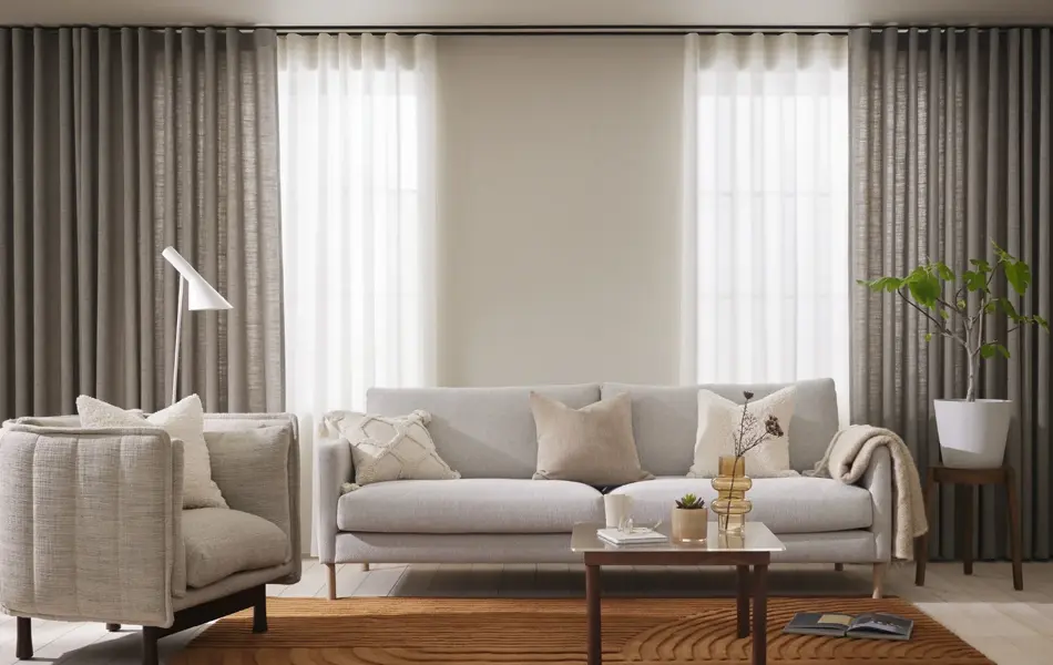 Stue med lyse sofaer og grå gardiner