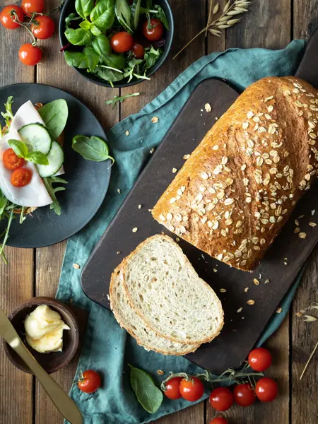 Miljøbilde med delvis oppskjært havrebrød-tomater-smør