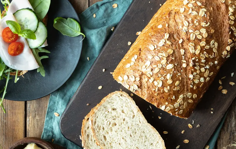 Miljøbilde med delvis oppskjært havrebrød-tomater-smør