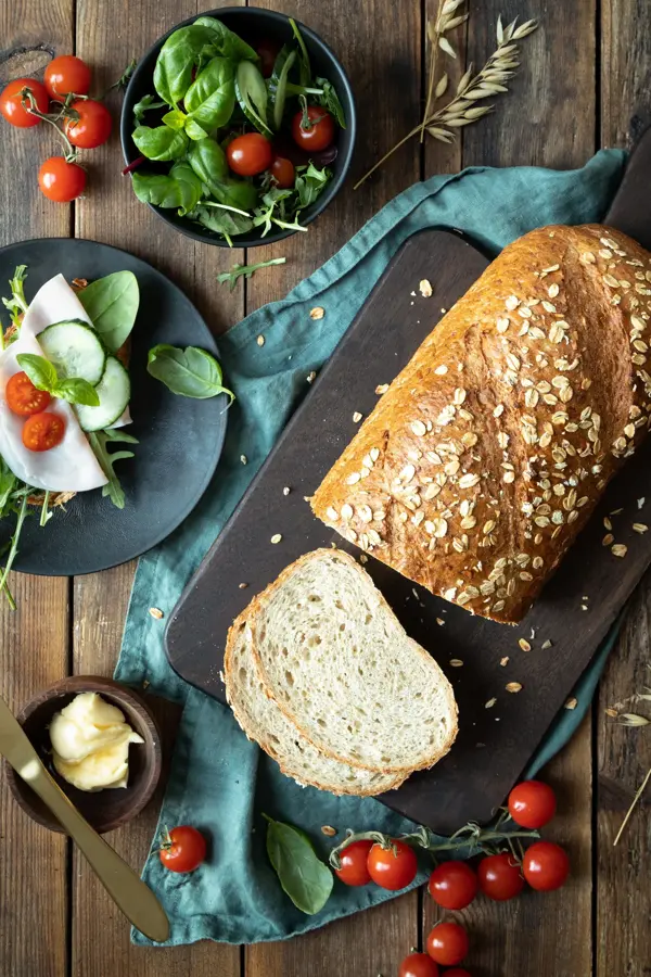 Miljøbilde med delvis oppskjært havrebrød-tomater-smør