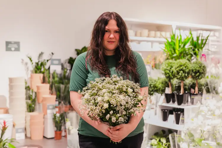 Kvinne som holder en bukett blomster i hendene
