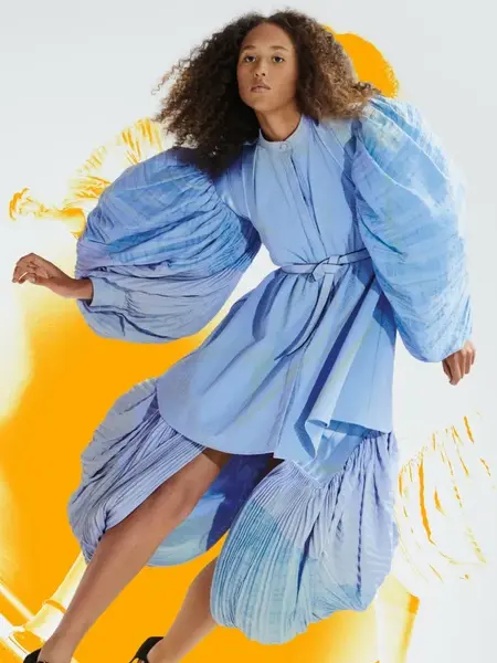 Dame med en stor lyseblå kjole og mørk stort krøllete hår 