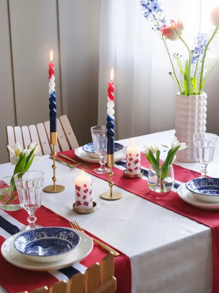Bord dekket til 17. mai med blomster, stearinglys og flaggløpere