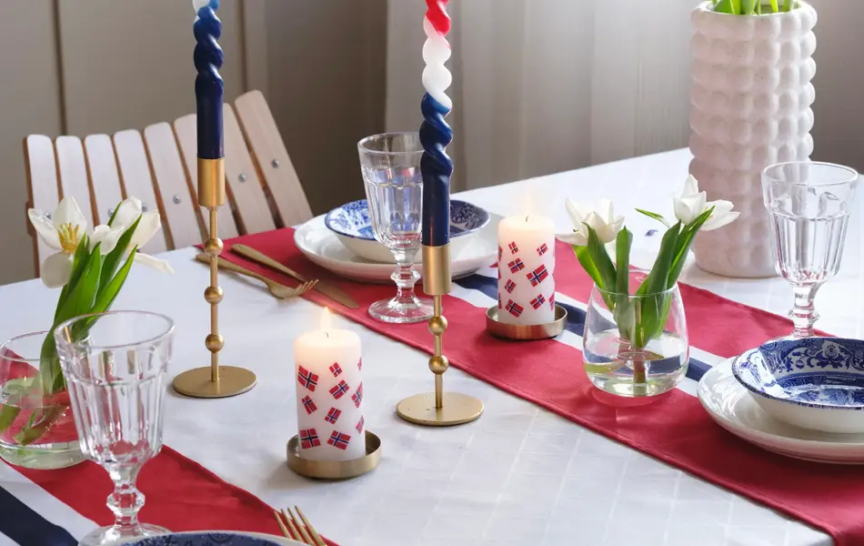 Bord dekket til 17. mai med blomster, stearinglys og flaggløpere