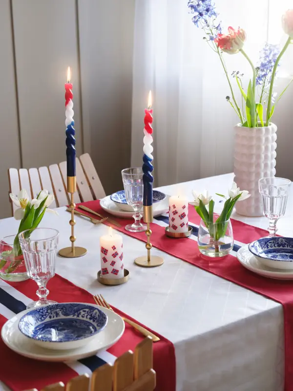 Bord dekket til 17. mai med blomster, stearinglys og flaggløpere