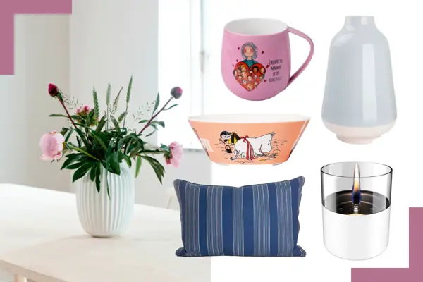 Kähler vase med blomster på et bord, rosa krus, lyseblå vase, Mummie-bolle, blåstripete pute og bordlykt.