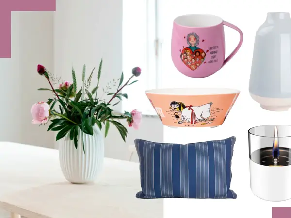 Kähler vase med blomster på et bord, rosa krus, lyseblå vase, Mummie-bolle, blåstripete pute og bordlykt.