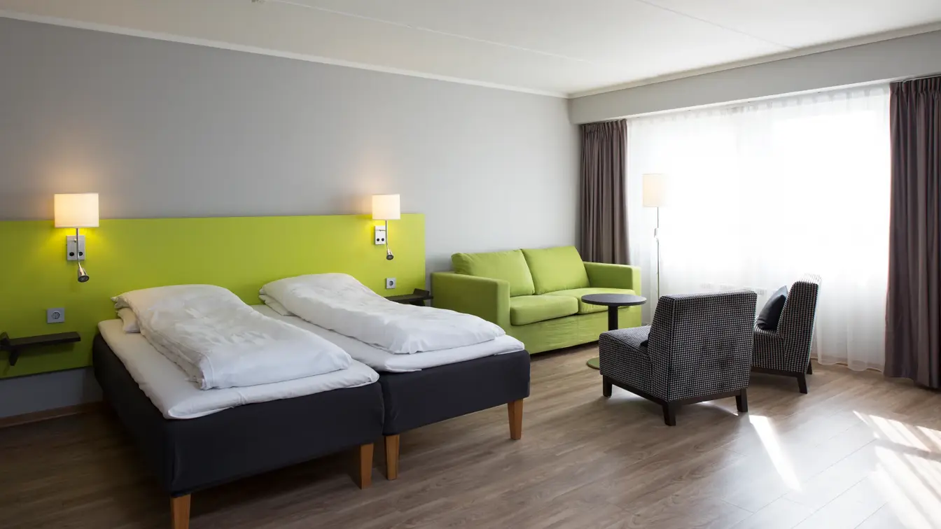 Seng o sittegruppe med sofa og to stoler i superior rom på Thon Hotel Hallingdal