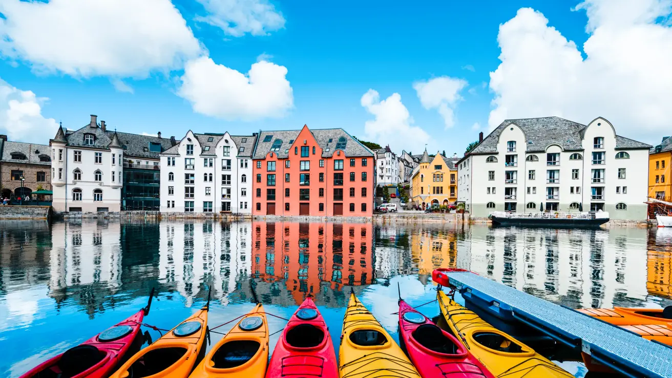 7 gule og røde kajakker ligger på land ved vannkanten i Ålesund.