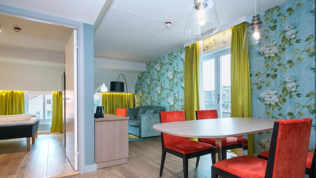 Bord og stoler, sofagruppe og separat soverom i suiten på Thon Hotel Tønsberg Brygge