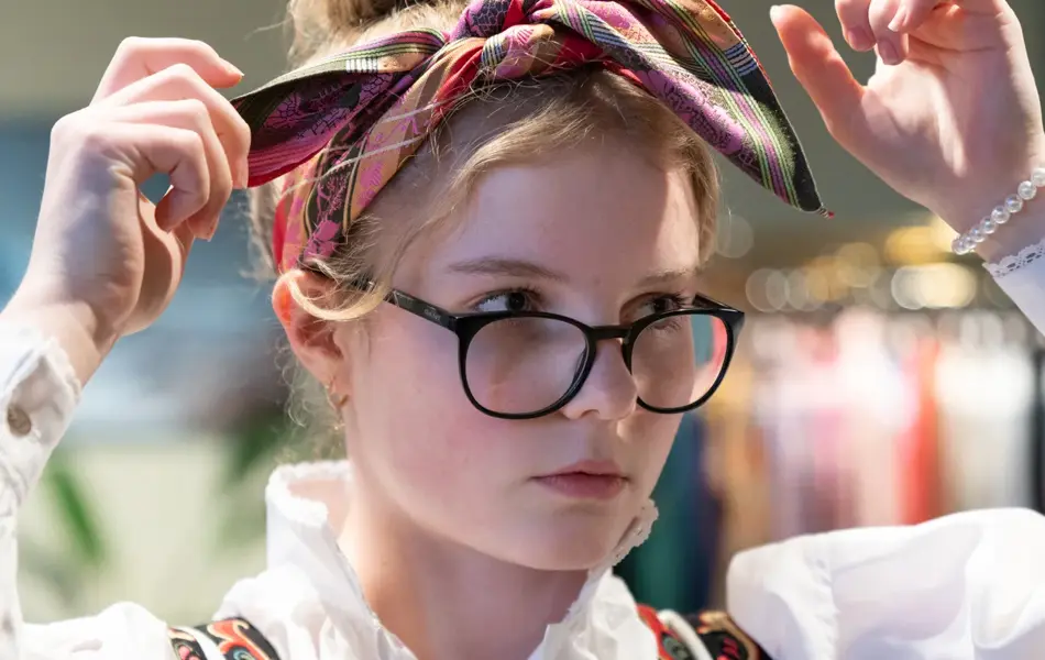 Hos Embla, jente prøver tørkle i håret