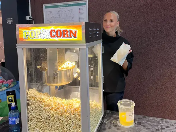 Dame står ved popcornmaskin