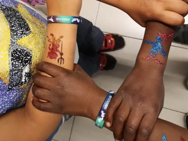 Bilde av barns hender med glitter tattoveringer på armene