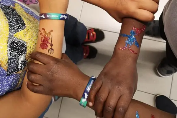 Bilde av barns hender med glitter tattoveringer på armene