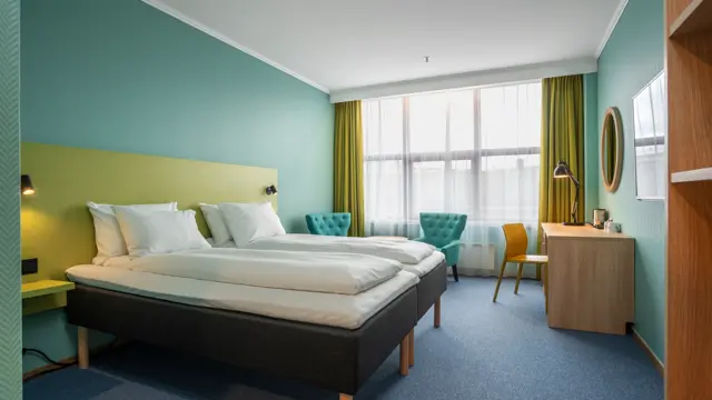 Vindu, gule gardiner, to turkise lenestoler, skrivebord, speil, twin beds, gul stol, turkise vegger