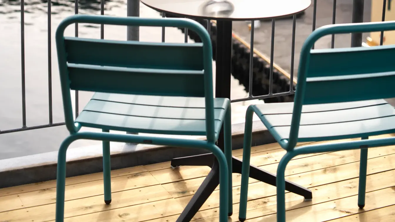 Balkong med utsikt over vannet, to stoler, rundt bord