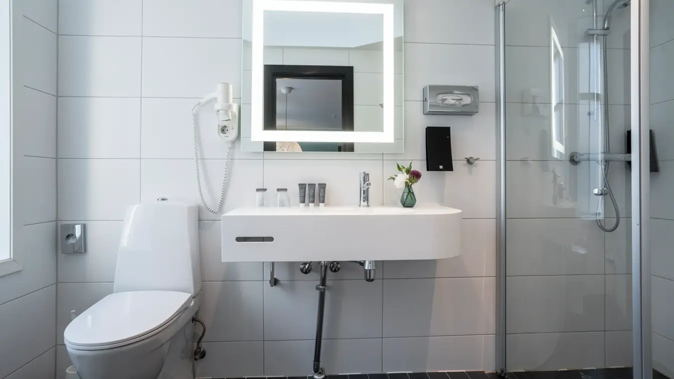 Vegghent servant med badeartikler, speil med led lys og dusj på bad i junior suite på Thon Hotel Maritim