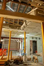 Innvendige bilder fra oppussing i Kjøpmannsgata 15 i Trondheim: Betong, tre og gule stolper. Nytt og gammelt treverk. Brutte etasjeskillere.