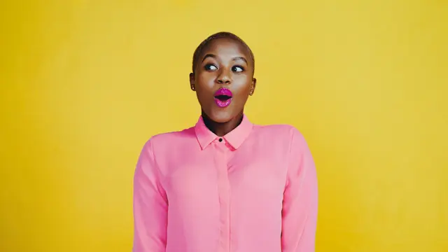 Cropped shot of an attractive young woman looking curious and surprised in studio against a yellow background