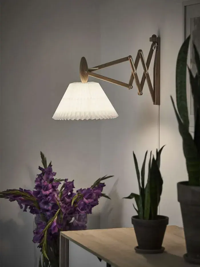 Vegglampe på en grå vegg ved en skjenk med potteplanter på.