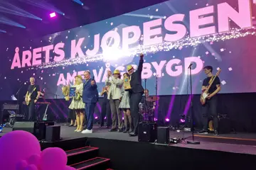 Vinnerne fra AMFI Vågsbygd på scenen, med Årets Kjøpesenter i store bokstaver på skjerm