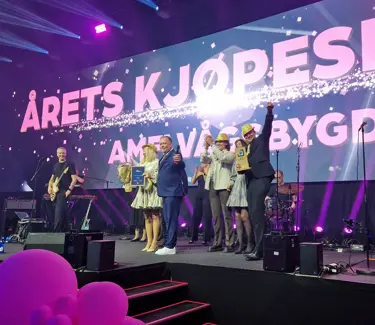 Vinnerne fra AMFI Vågsbygd på scenen, med Årets Kjøpesenter i store bokstaver på skjerm