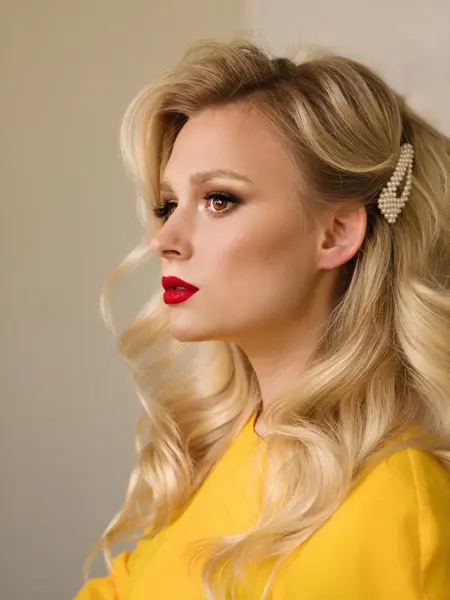 Side view closeup portrait of woman with creative elegant blondes hairstyle. Medium length wave blonde hair. Perfect red matte lips. Hollywood makeup. Stylish look. Beauty service concept.