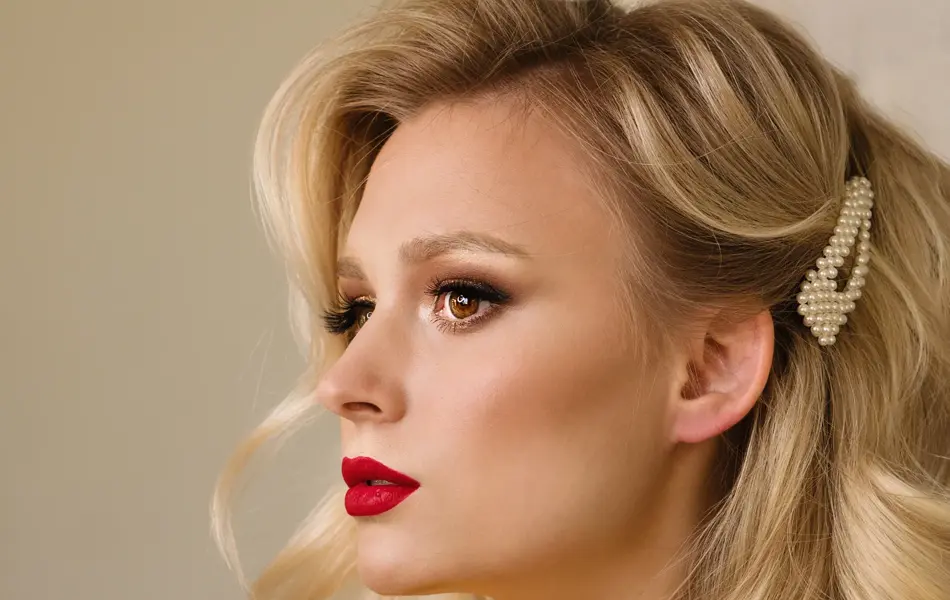 Side view closeup portrait of woman with creative elegant blondes hairstyle. Medium length wave blonde hair. Perfect red matte lips. Hollywood makeup. Stylish look. Beauty service concept.
