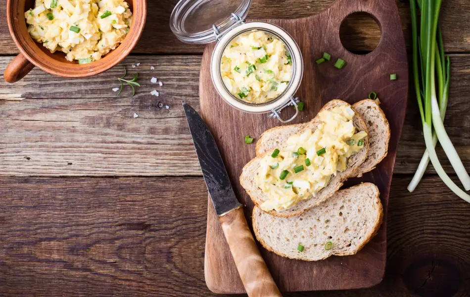 Egg paste sandwich with spring green onion for healthy and delicious brunch on rustic wooden cutting board viewed from above