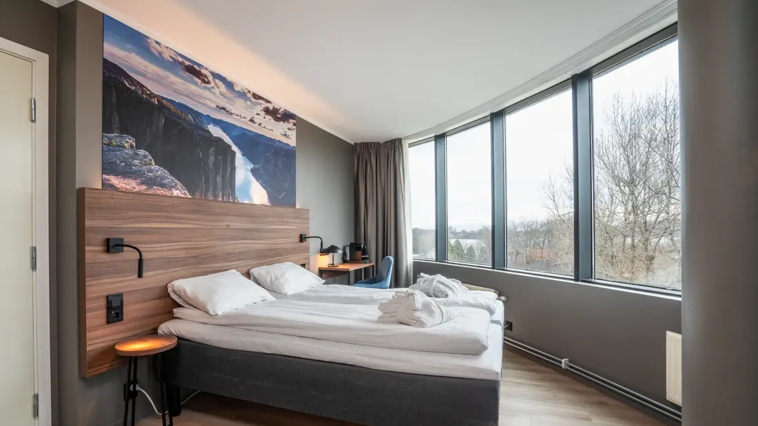 Superiorrom med dobbeltseng nattbord, skrivebord og hvilestol, 4 store vinduer, sengegavl i tre med panoramabilde fra Preikestolen over. Parkettgulv.