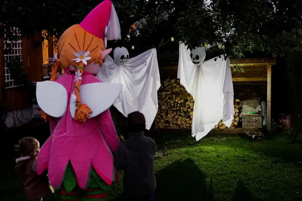 amfelia og to barn ser på spøkelsesfigurer som henger i treet