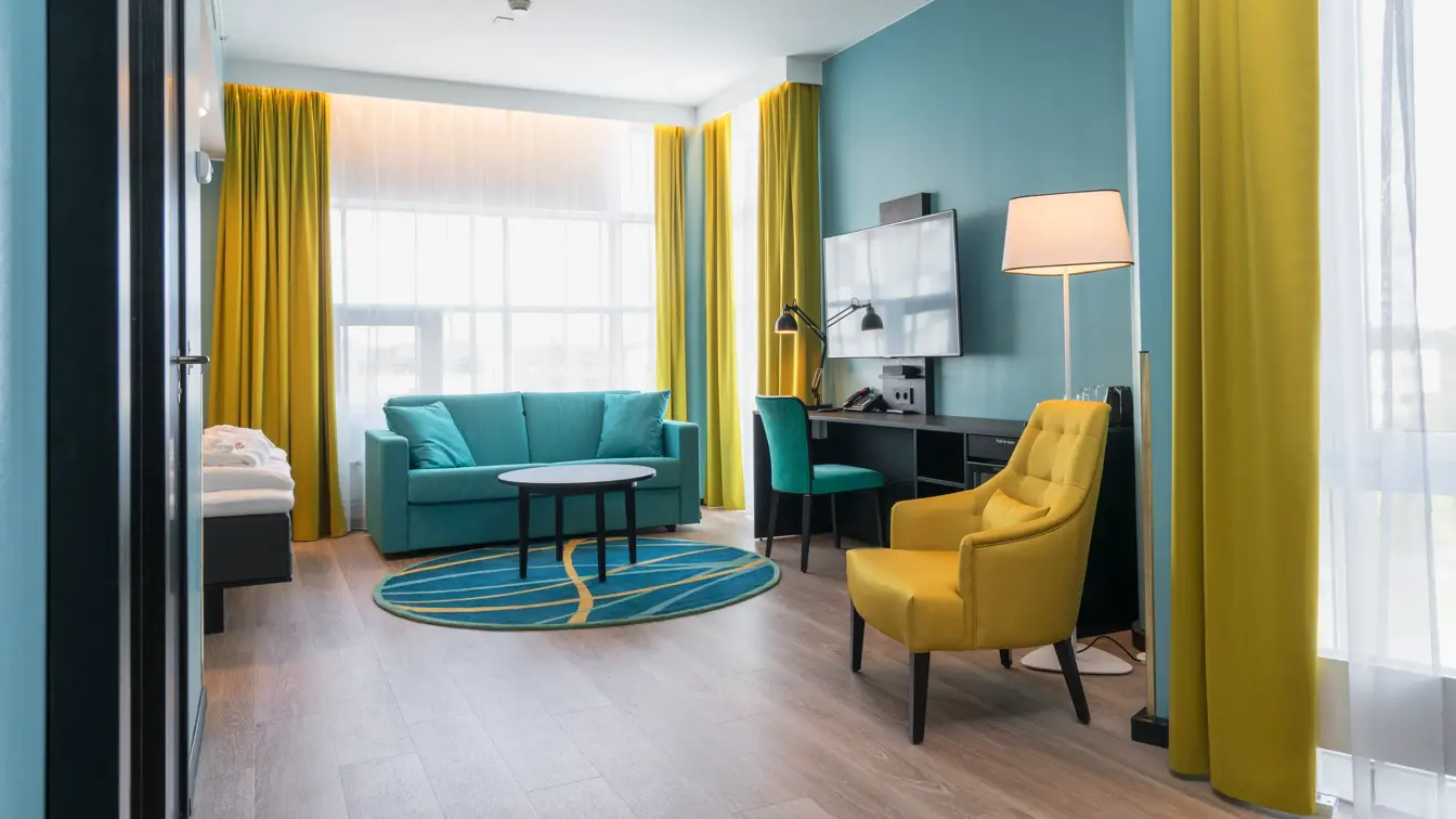 Superior room med turkise og gule detaljer, sofa, lenestol, gardiner