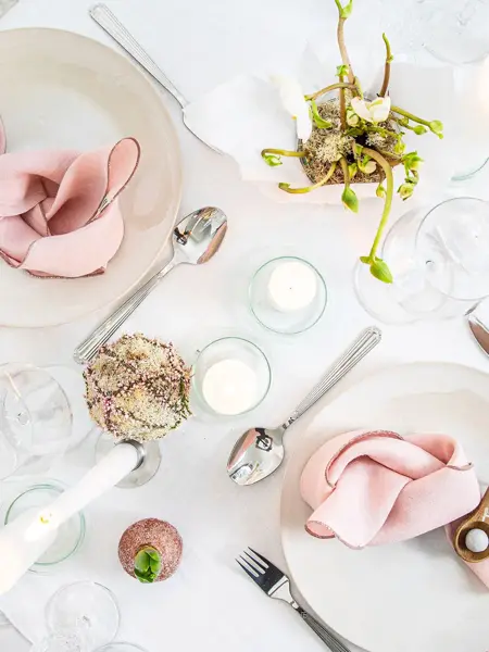 Langbord dekker til gjester med rosa servietter og grønn naturlig dekorasjon