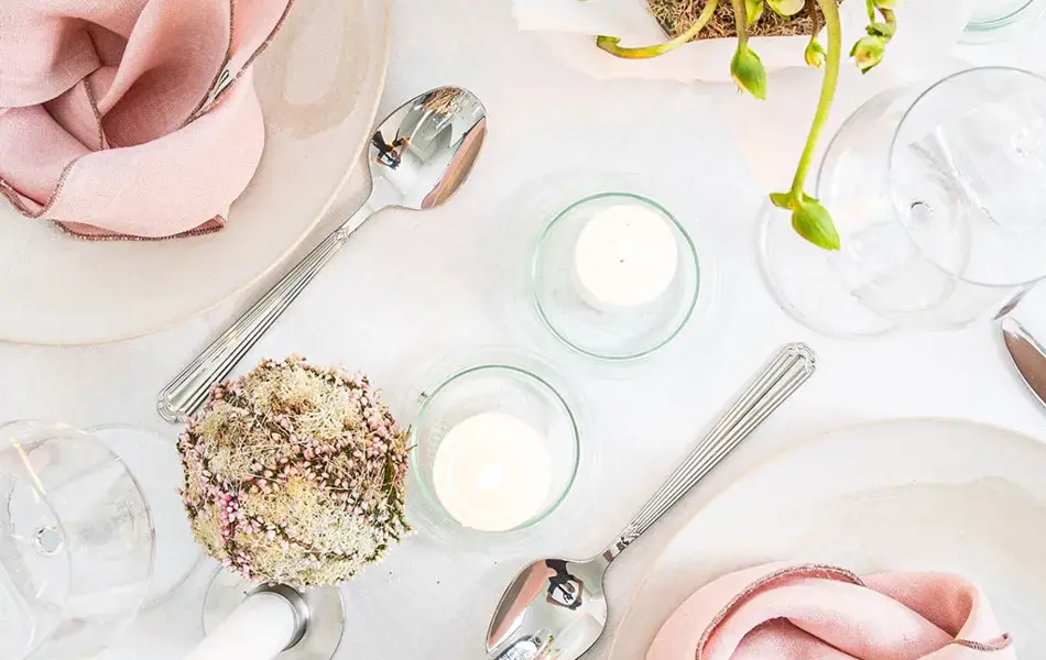 Langbord dekker til gjester med rosa servietter og grønn naturlig dekorasjon