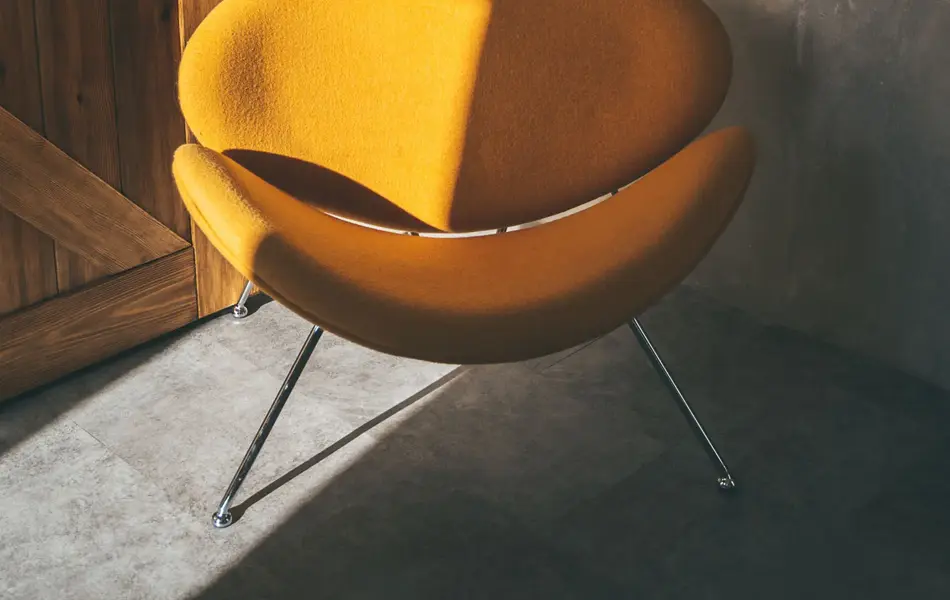 Gul stol i rom i grå betong og med en tredør i bakgrunnen.