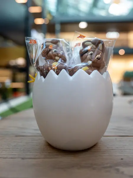 Et halvt kjeramik egg med sjokolade kaniner på pinne 