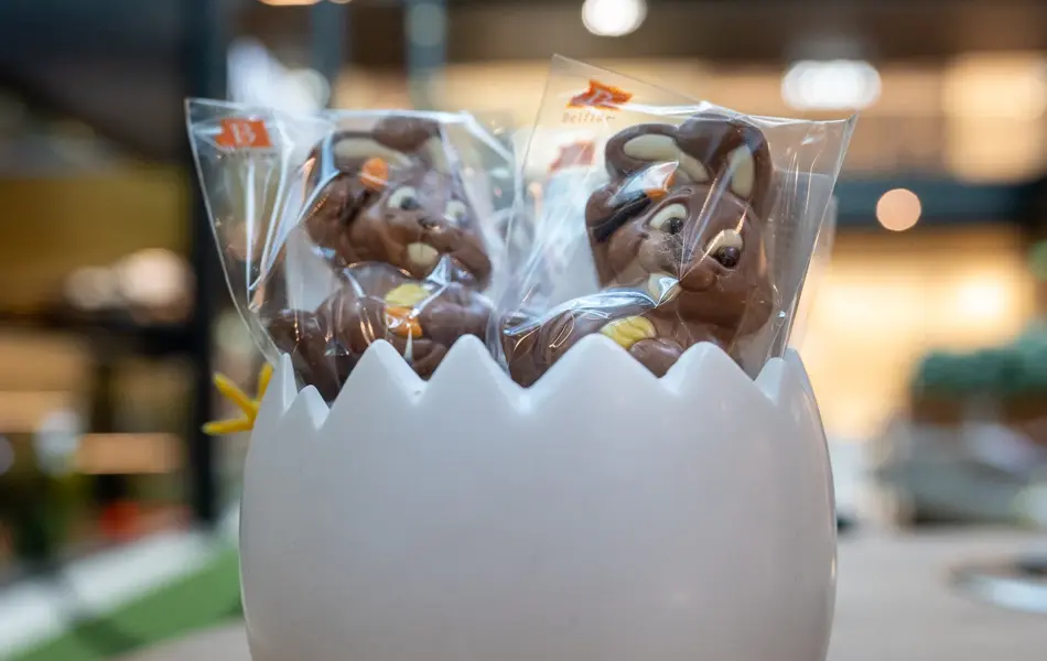 Et halvt kjeramik egg med sjokolade kaniner på pinne 